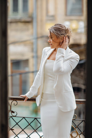 a beautiful, confident woman in a white suit on the balcony of the old building.の写真素材