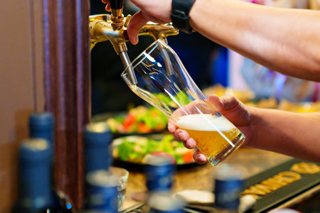 mens hands pour beer into a beer tap glass.の写真素材
