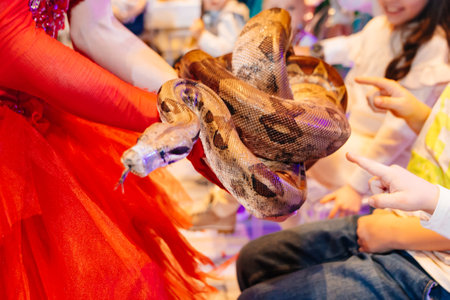 a python in the hands of an actress at a performance for children with animals.の写真素材