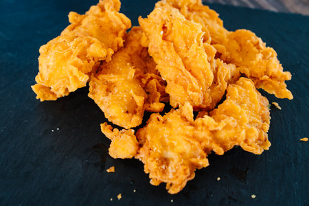 meat strips on a black tray. strips of meat fried in breading.の写真素材