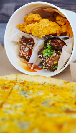 cheese pizza and caramelized chicken, meat strips in paper bucketの写真素材