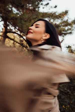 a brunette woman in a raincoat walks through the streets of the autumn city.