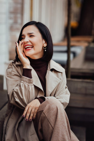 portrait of a happy attractive brunette in an autumn coat on a city street.の写真素材