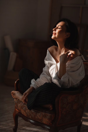 sexy attractive relaxed brunette woman in a white shirt with bare shoulders.の写真素材