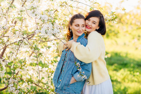 two attractive women hugging in a spring garden.の写真素材