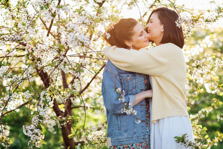 two attractive women hugging in a spring garden.の写真素材