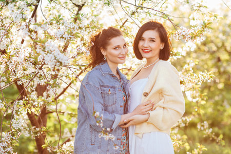 two attractive women hugging in a spring garden.の写真素材
