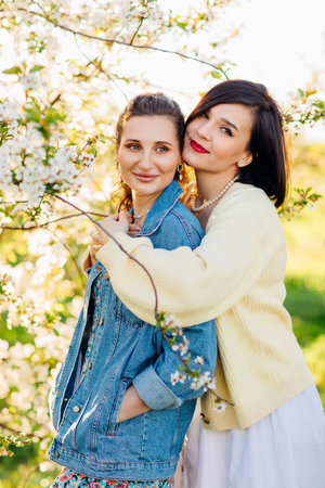 two attractive women hugging in a spring garden.の写真素材