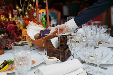 table setting for a festive dinner. waiter places a plate of bread on the table.の写真素材