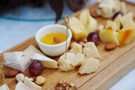 wooden tray with cheese cuts, nuts, grapes and honey.の写真素材
