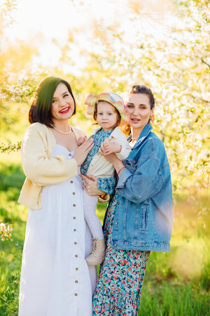 two attractive women with a little girl in their hands in a spring garden.の写真素材