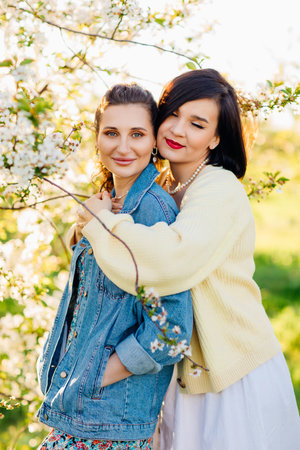 two attractive women hugging in a spring garden.の写真素材