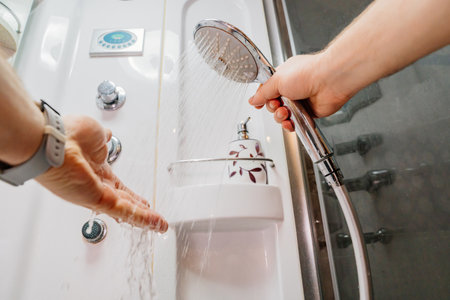 Mens hands turn on the water and check the operation of the shower hose.の写真素材