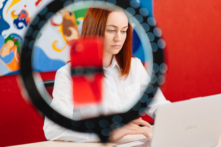 a red-haired woman works at the computer and conducts a live broadcast