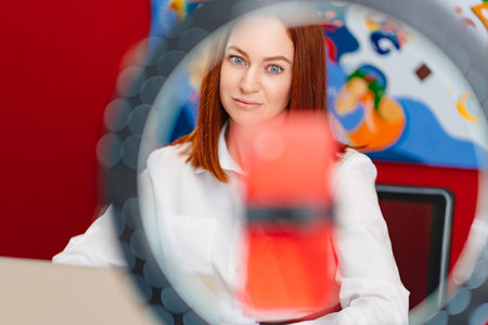 a red-haired woman works at the computer and conducts a live broadcast