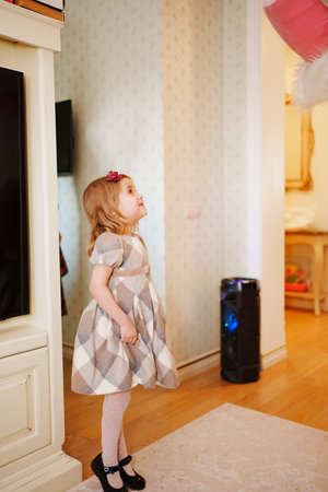 a cute little girl stands in a room waiting for a surprise.の写真素材