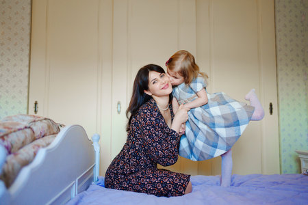 mother and daughter play and have fun on the bed.