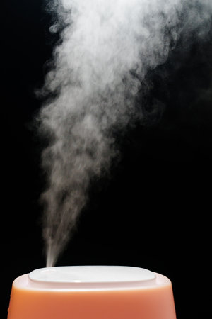 Steam from pink humidifier on a black background.の写真素材