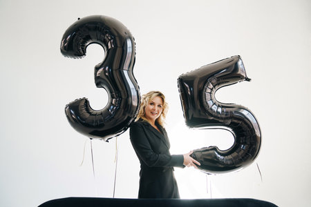 a sexy blonde in a black on background of balloons of numbers thirty-fiveの写真素材