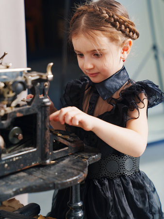 cute little girl with pigtail in a black dress prints on a retro typewriterの写真素材