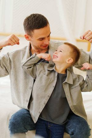 dad plays with his son and jokingly measures strengthの写真素材