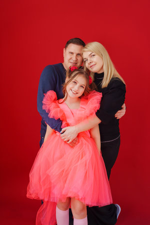 father, mother and daughter in a beautiful elegant dress on a red backgroundの写真素材