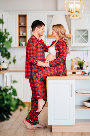a pregnant woman and a man in pajamas in the kitchenの写真素材