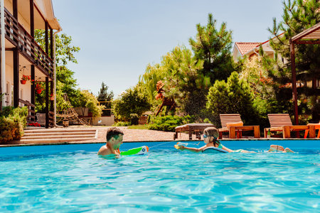 Father and daughter have fun with water guns in the pool.