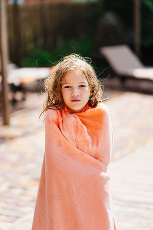 Cute teenage girl with wet hair and in a towel after swimming in the pool.の写真素材