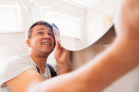 A man hangs a large round mirror in the bathroom.の写真素材