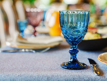 glasses of colored glass on a table with a blue tablecloth.の写真素材