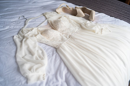 The brides shoes and wedding dress on the bed.の写真素材