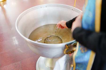 the priest dips the brush into Baptismal font in the Orthodox Church.