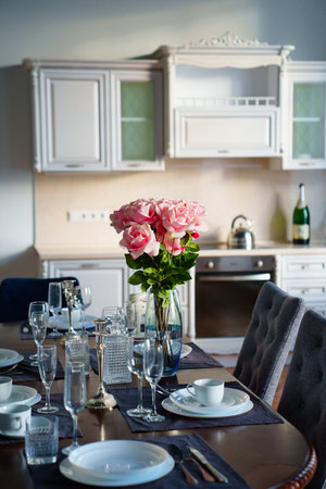 table with dishes and bouquet of roses in the bright kitchen of the living roomの写真素材
