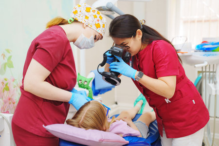 The pediatric dentist takes photos of the teeth before or after treatment.のeditorial素材