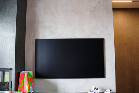 A large black TV on a gray wall in a modern interior.の写真素材