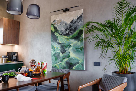 interior with gray walls, large houseplant and a large painting depicting mountainsのeditorial素材