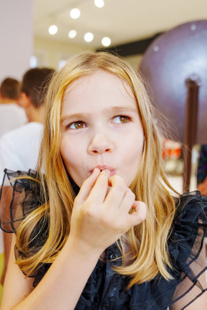 A teenage girl in a black dress eats candy surprises at a childrens partyの写真素材