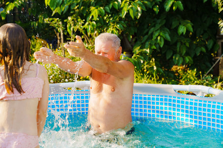 Grandpa and granddaughter play and have fun in the pool.の写真素材