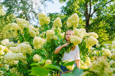 Cute teenage girl in flowering hydrangea bushes.
