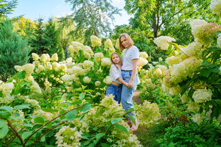 mother and daughter in flowering hydrangea bushes.