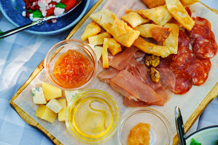 A wooden tray with chips, honey, sauce, cheese and meat appetizers on the banquet table. Beautiful...