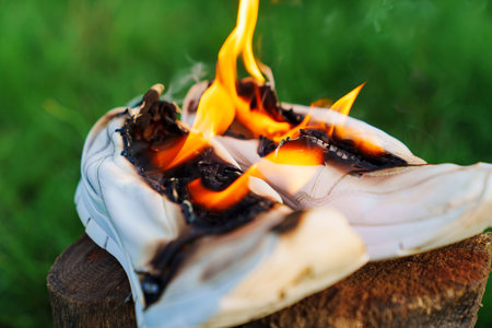 Burning leather sports shoes. Sneakers or gym shoes on fire stand on the Stump.の写真素材