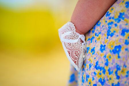 Baby with feet in lace shoes in his mother's arms. Mother's love and tenderness.の写真素材