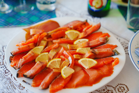 Slicing salted red fish with lemon on a plate. A delicious delicacy appetizer.