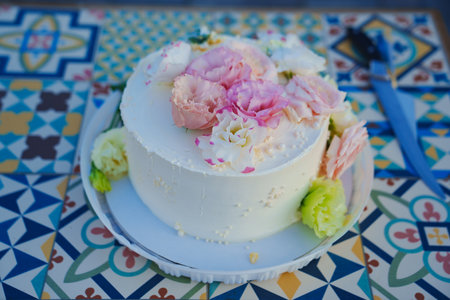 Classic white cake decorated with pink and white fresh flowers. Simple and effective decor for...