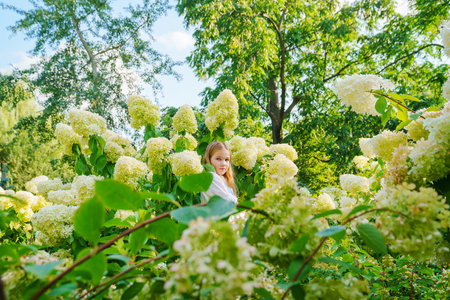 Cute teenage girl in flowering hydrangea bushes.