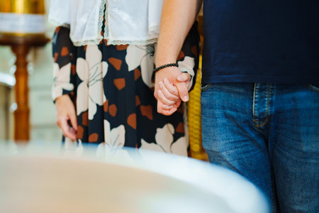 A man and a woman holding hands at a church service. without a face