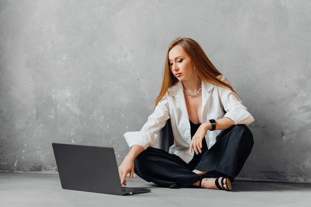 Business woman in white shirt and black pants working on laptop on the floorの写真素材