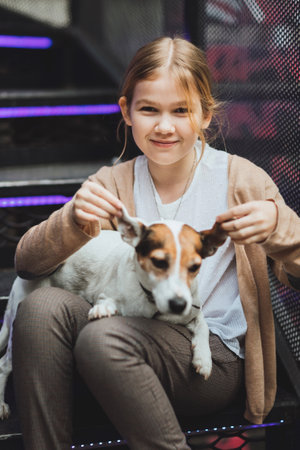 Cute teenage blonde girl with dog on the steps.の写真素材